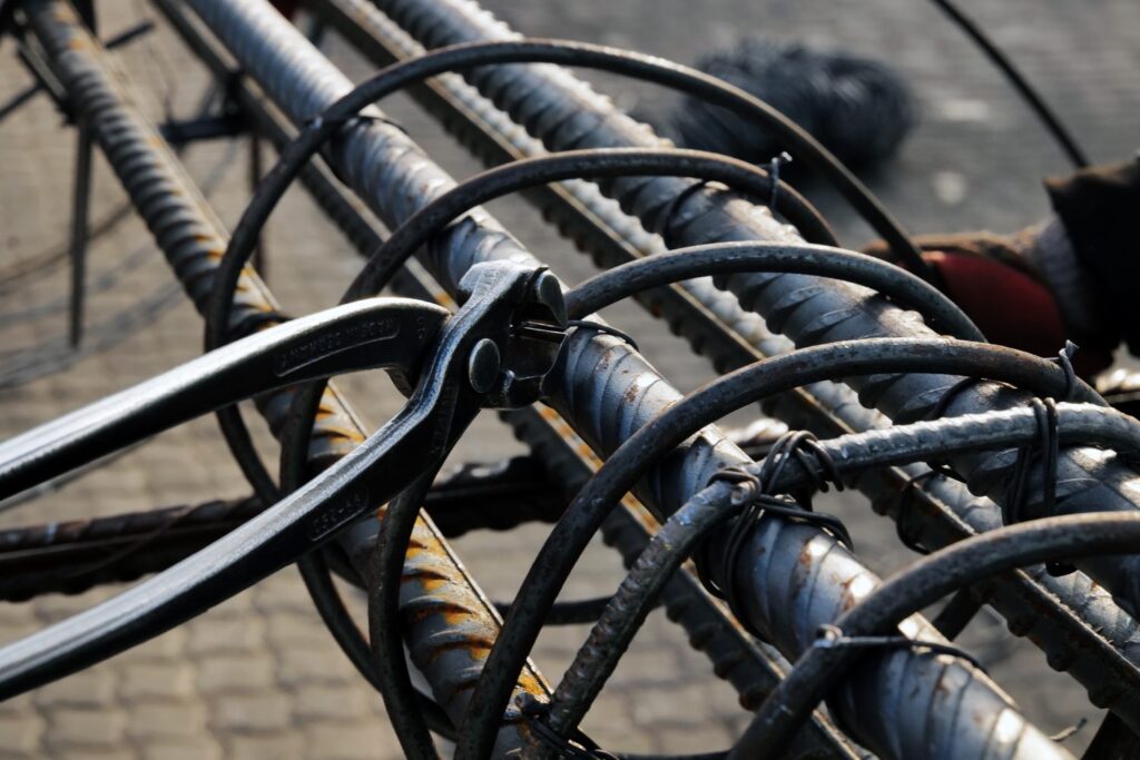 Steel fixer tying binding wire onto reinforcing bar with fixing pincers on an RMS site