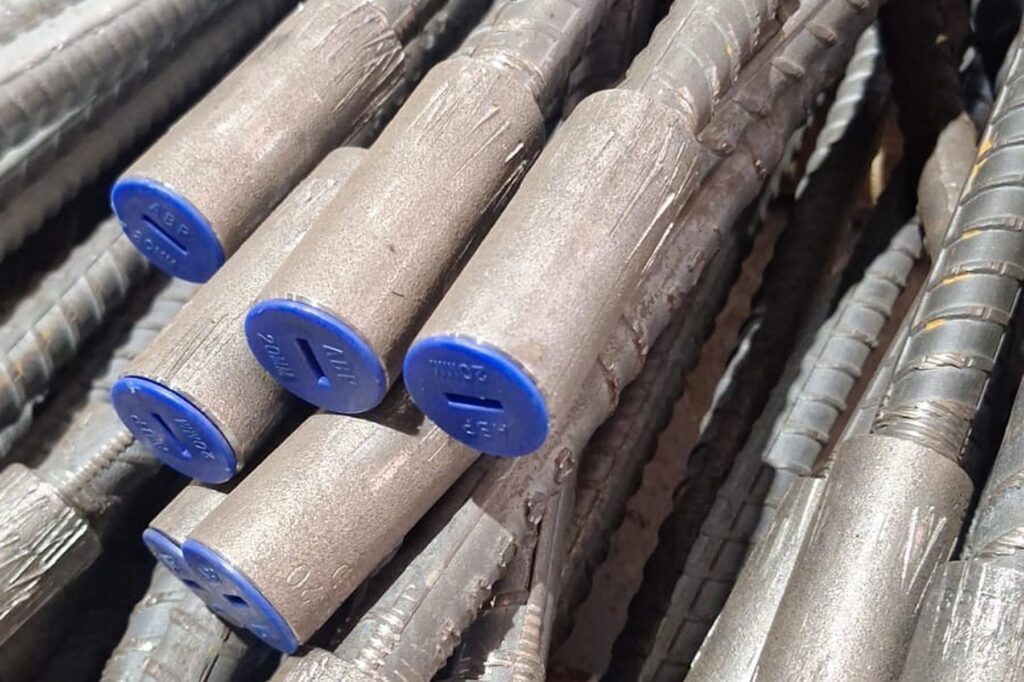 Reinforcing Bar Couplers Compared: Choosing the Right System for Your Project 1 Threaded reinforcing bars with blue protective end caps ready for couplers at RMS Durban